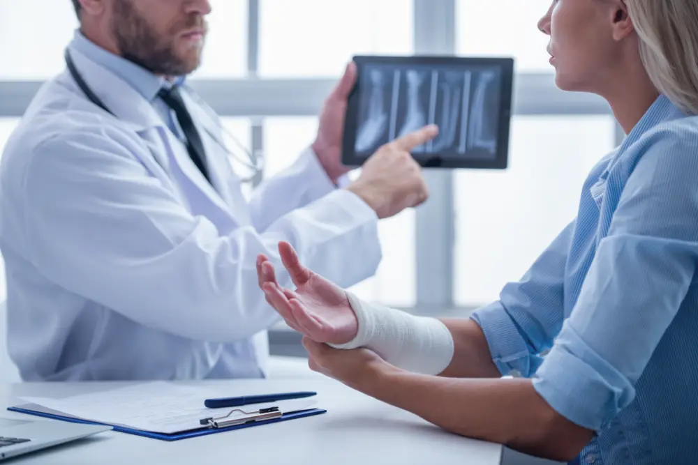 Doctor reviewing a spinal X-ray on a tablet with a patient